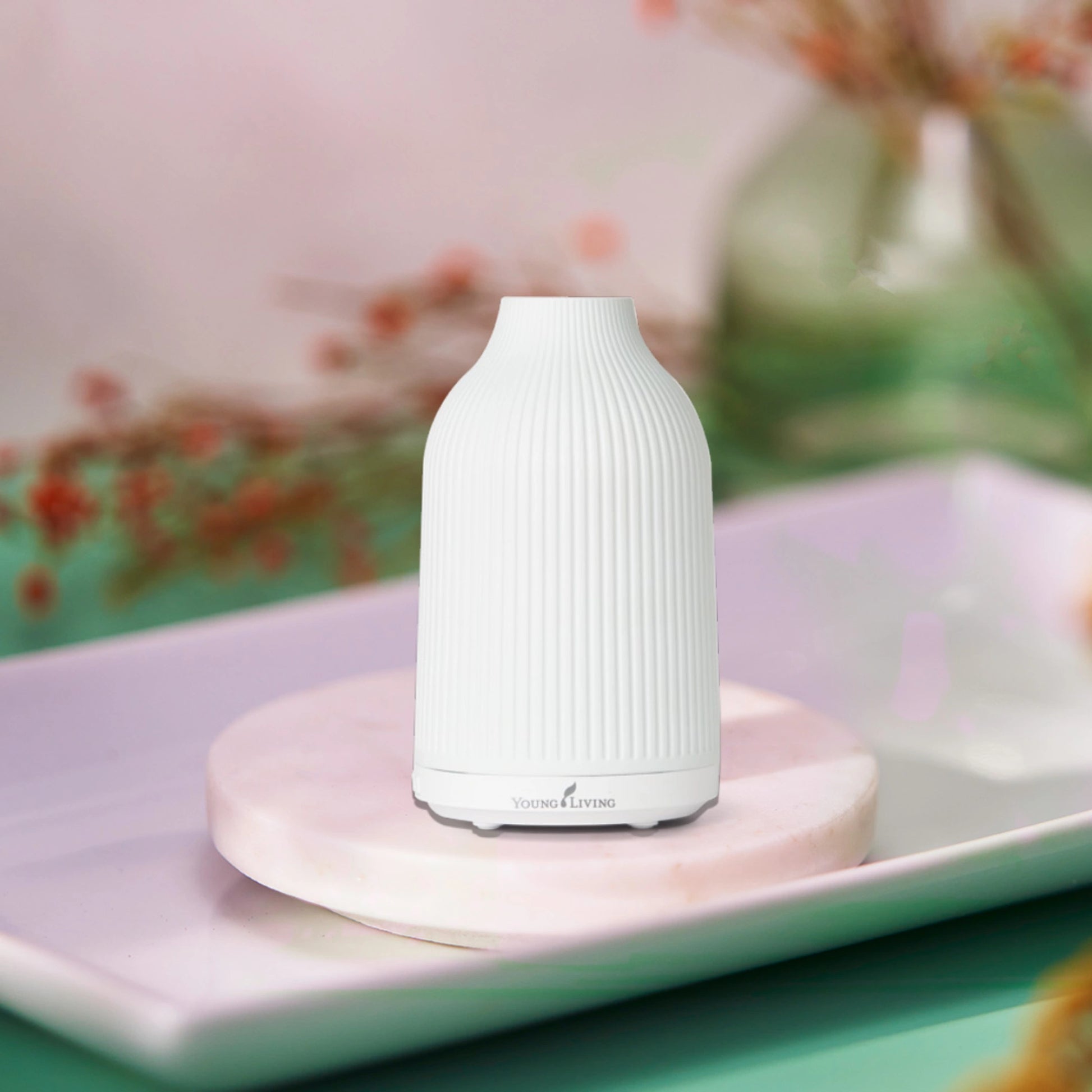 Stijlvolle witte diffuser van Young Living op marmeren ondergrond, perfect voor aromatherapie bij hormonale disbalans, stress of behoefte aan meer rust en balans in het dagelijks leven.