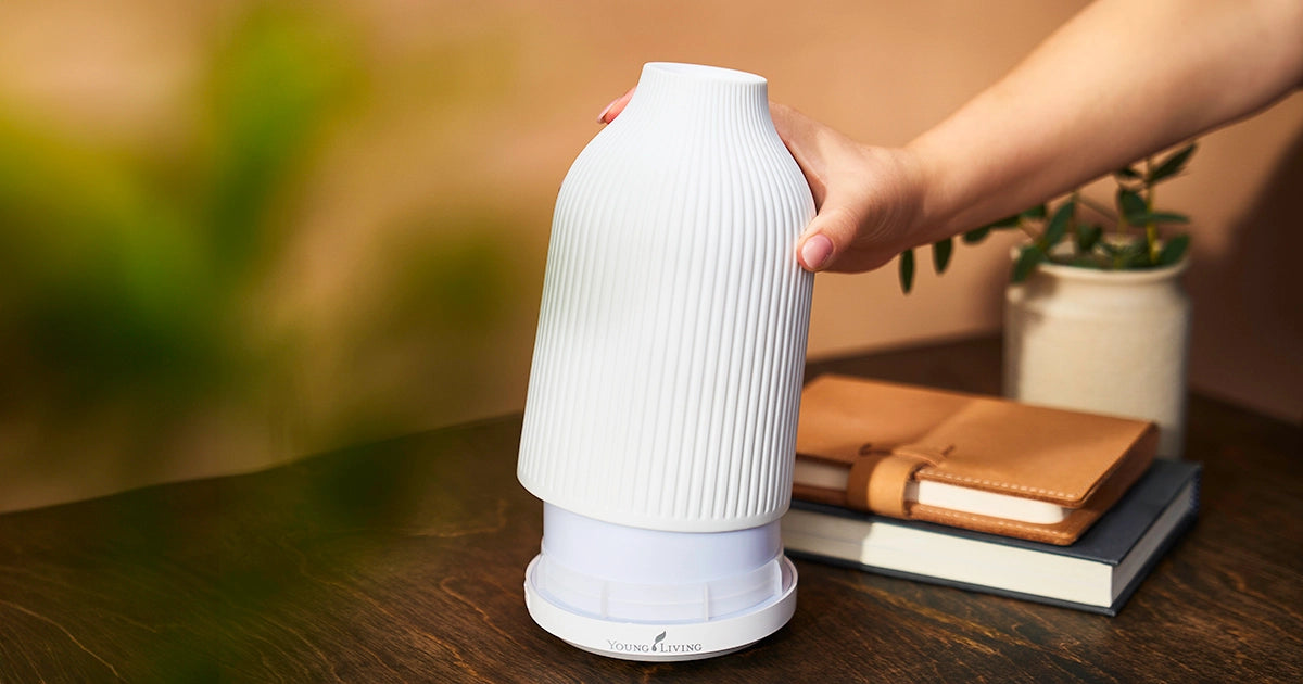 Hand plaatst de artisanaal vervaardigde Adobe Mist diffuser op een houten tafel – elegant keramisch design dat rust brengt in elke ruimte.