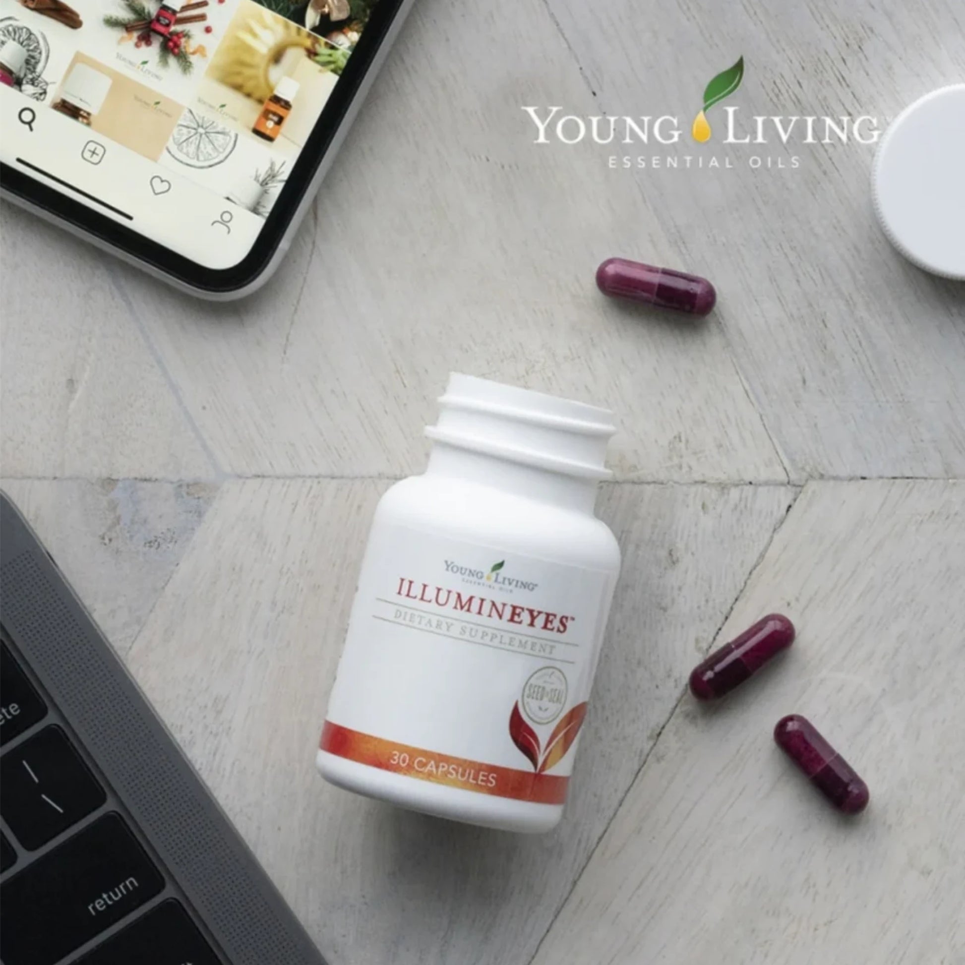 Pot Illumineyes supplement van Young Living op bureau met laptop en smartphone – natuurlijke bescherming tegen blauw licht en ondersteuning van het zicht.