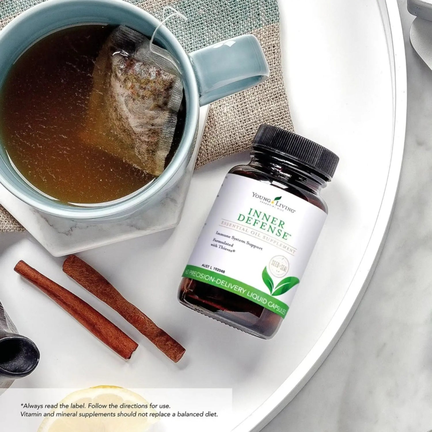 Inner Defense supplement van Young Living naast een kop thee en kaneel – ideaal als natuurlijke kuur voor weerstand, reiniging en virusbescherming.