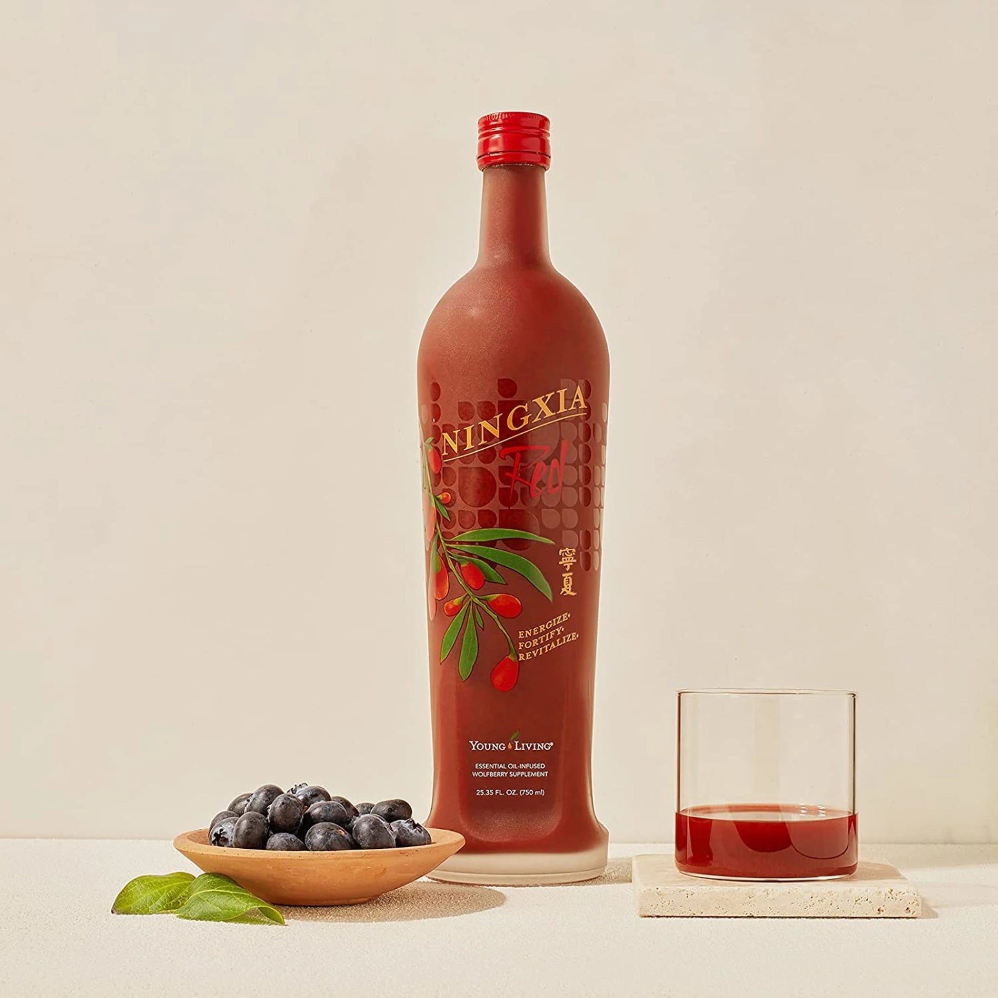 NingXia Red fles met glas en blauwe bessen – antioxidantenrijke drank van Young Living ter ondersteuning van herstel bij uitputting, verminderde weerstand en allergieën.