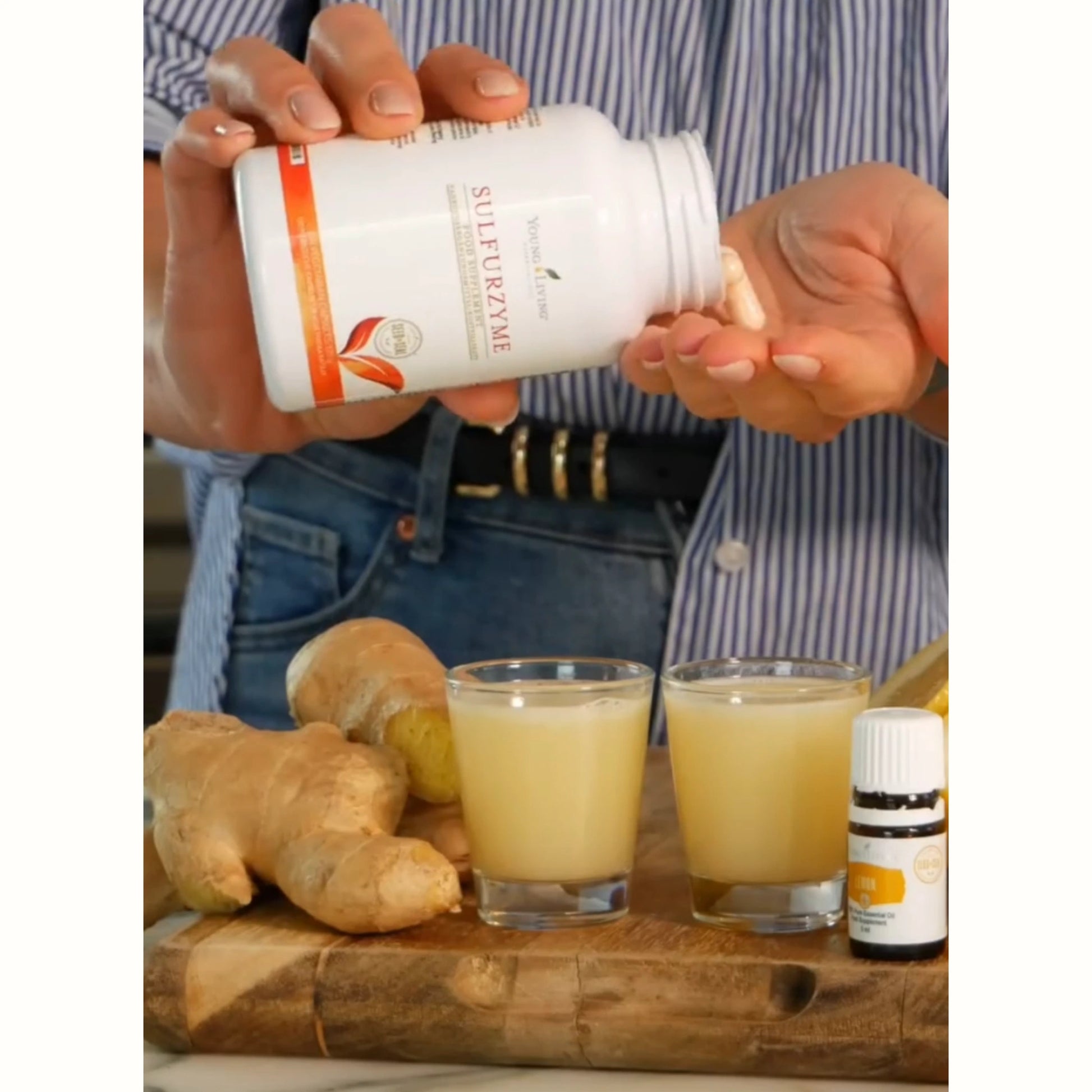 Hand met Sulfurzyme capsules en gembershot – natuurlijk supplement bij burn-out, vermoeidheid en herstel van het lichaam.