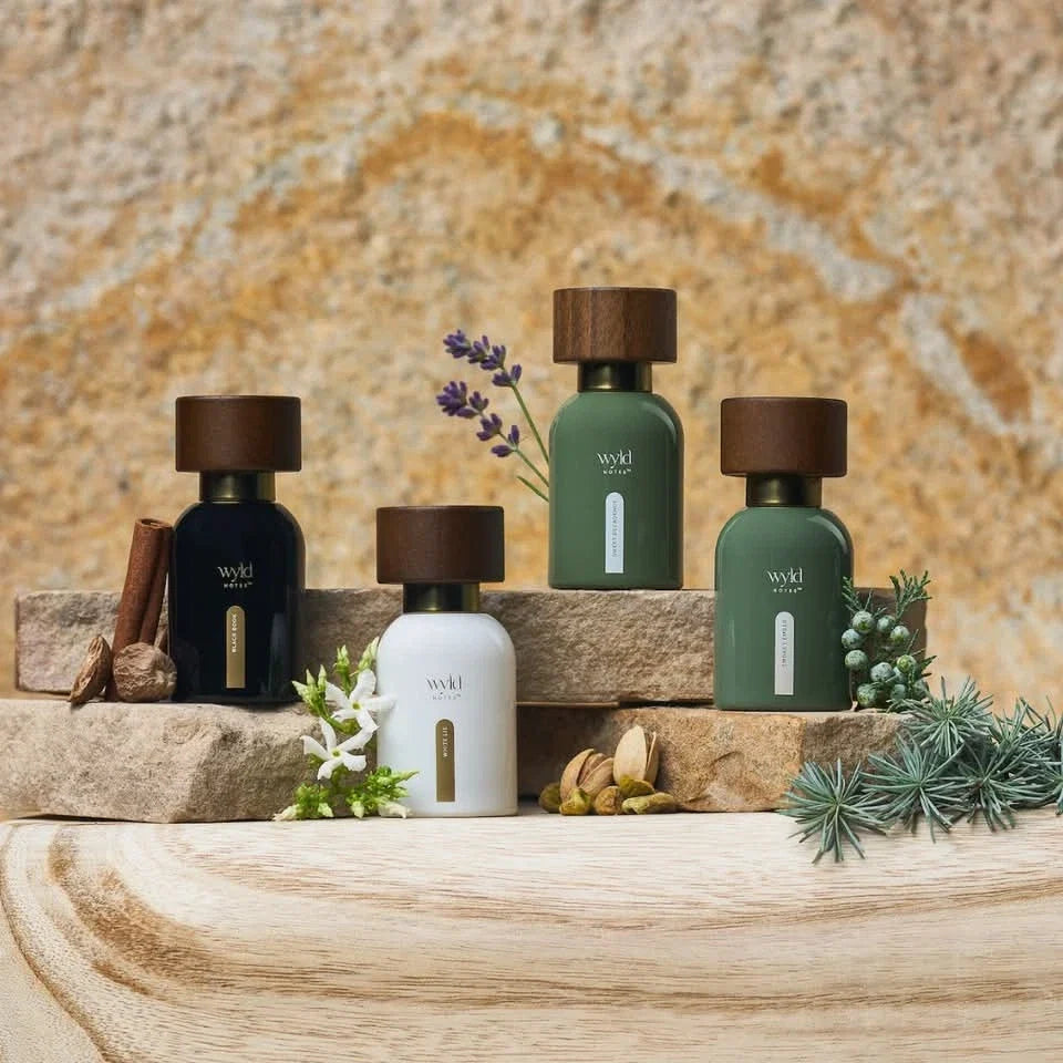Wyld Notes parfumcollectie met Sweet Decadence, Smokey Ember, White Lie en Black Book op natuursteen met botanische ingrediënten