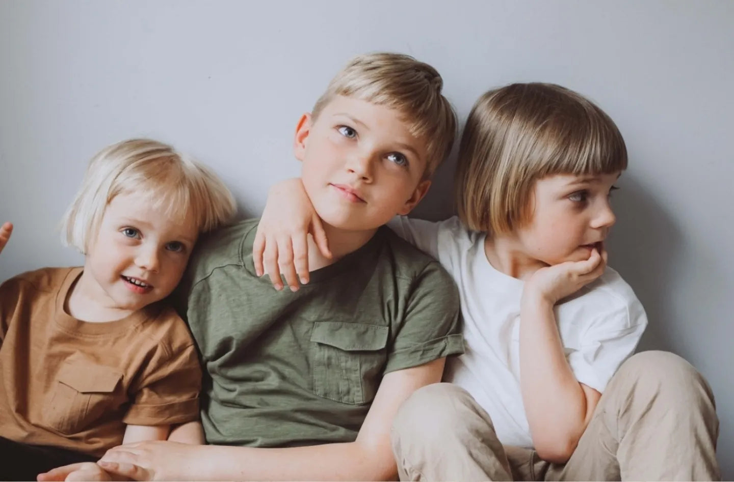 Drie jonge kinderen zitten samen op een bank, symbool voor de kracht van verbinding en veiligheid. Aromatherapie helpt kinderen in pleeggezinnen meer rust, balans en ontspanning te ervaren.