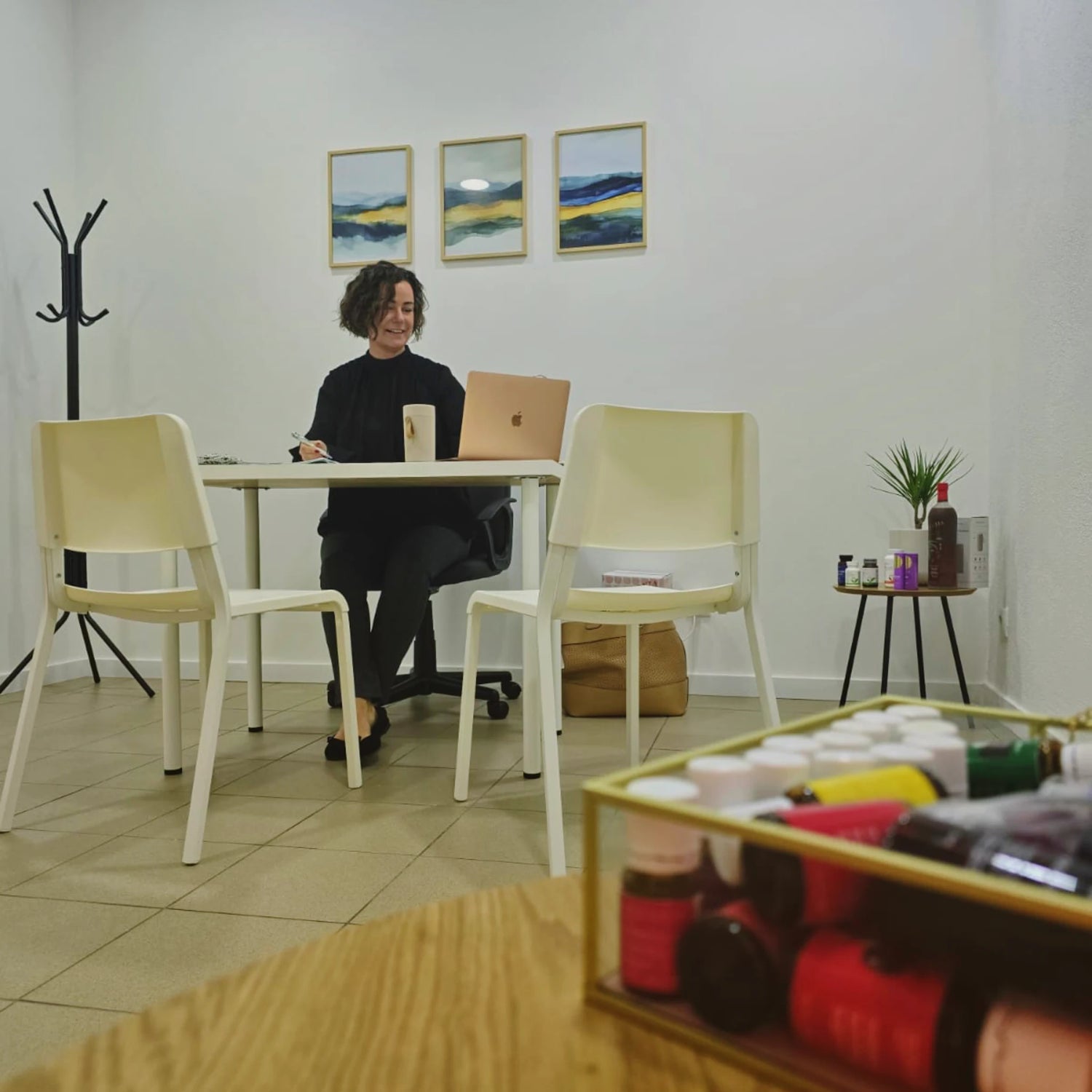 Certified naturopath Suzanne Shares consulting a client in her holistic health office in the Algarve, Portugal, seated at a desk with natural wellness products visible in a calm clinical setting.