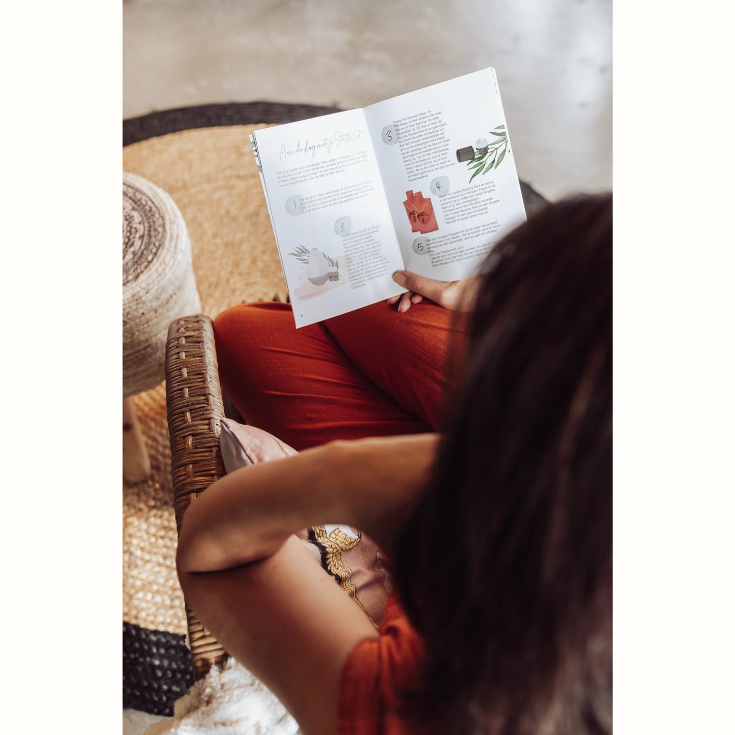 Vrouw leest een handleiding over het gebruik van essentiële oliën en diffusers, ideaal voor wie zoekt naar natuurlijke oplossingen voor stress, gewichtsbeheersing of midlife-uitdagingen.
