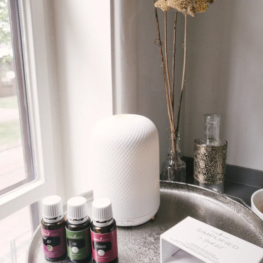 Set met Joy, Lime en Geranium oliën van Young Living naast een stijlvolle diffuser – een natuurlijke boost voor emotioneel welzijn en balans in huis.