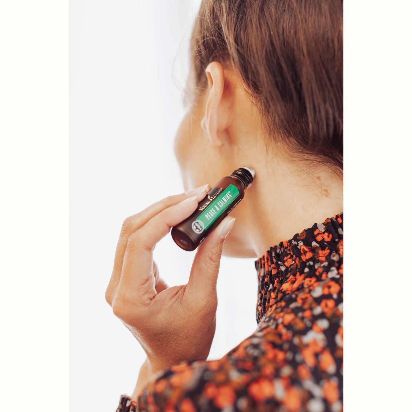 Vrouw gebruikt de troepvrije Peace & Calming Roll-On van Young Living als natuurlijk parfum in haar nek – helpt bij hoofdpijn, ondersteunt het aura en bevordert ontspanning zonder synthetische geurstoffen.
