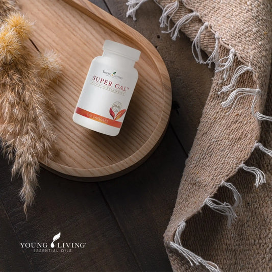 Pot Super Cal van Young Living op houten plateau met rustgevende texturen – ondersteunt ontspanning en helpt het zenuwstelsel kalmeren.