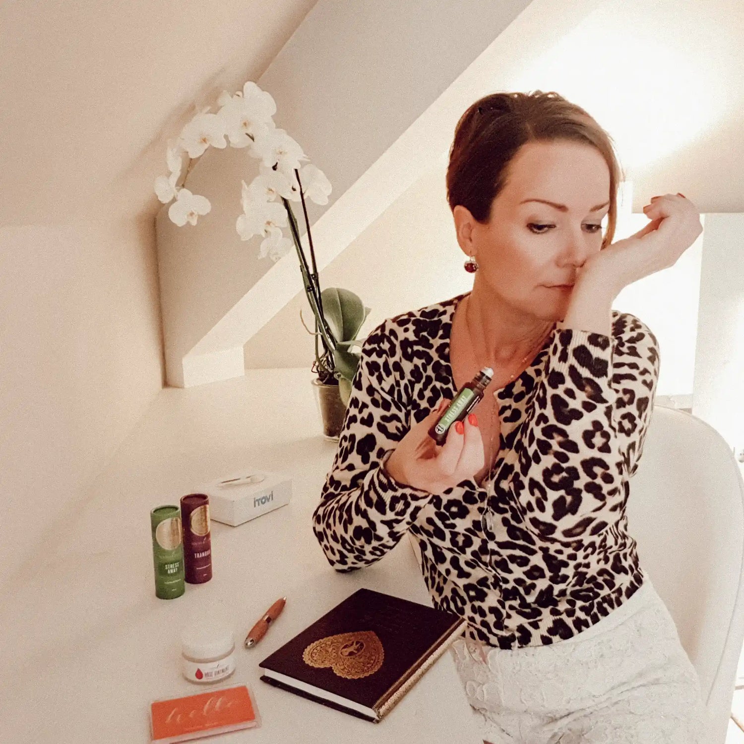 Suzanne in een ontspannen omgeving terwijl ze aan haar pols ruikt, waar ze net Young Living essentiële olie heeft aangebracht. Met 25 jaar ervaring in naturopathie helpt ze mensen met een holistische en gepersonaliseerde aanpak voor balans en welzijn.
