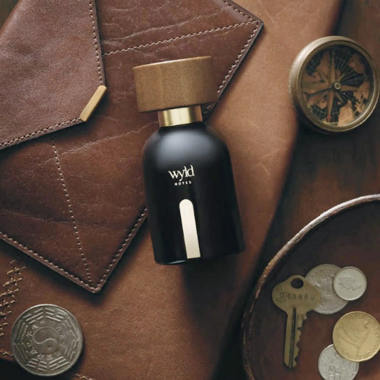Wyld Notes Black Book parfum op donker leer met kompas, sleutels en old money uitstraling.