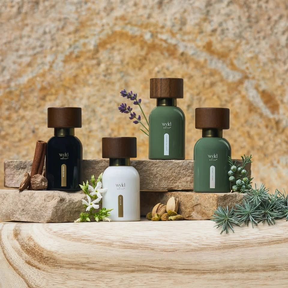 Wyld Notes parfumcollectie met Sweet Decadence, Smokey Ember, White Lie en Black Book op natuursteen met botanische ingrediënten