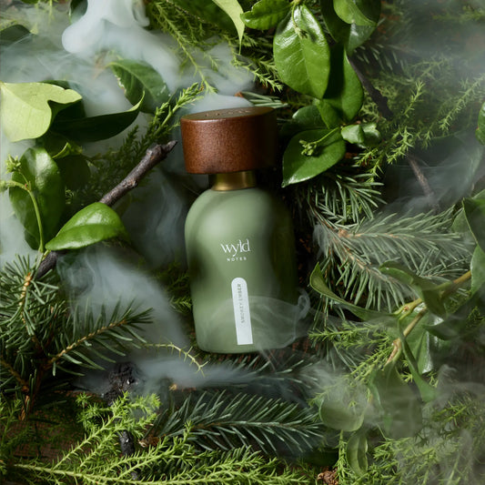 Wyld Notes Smokey Ember eau de parfum tussen groene bladeren, naaldtakken en zwevende rook.