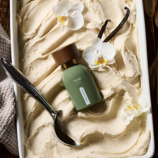 Sweet Decadence parfum van Wyld Notes in een romige vanille setting met witte orchideeën.