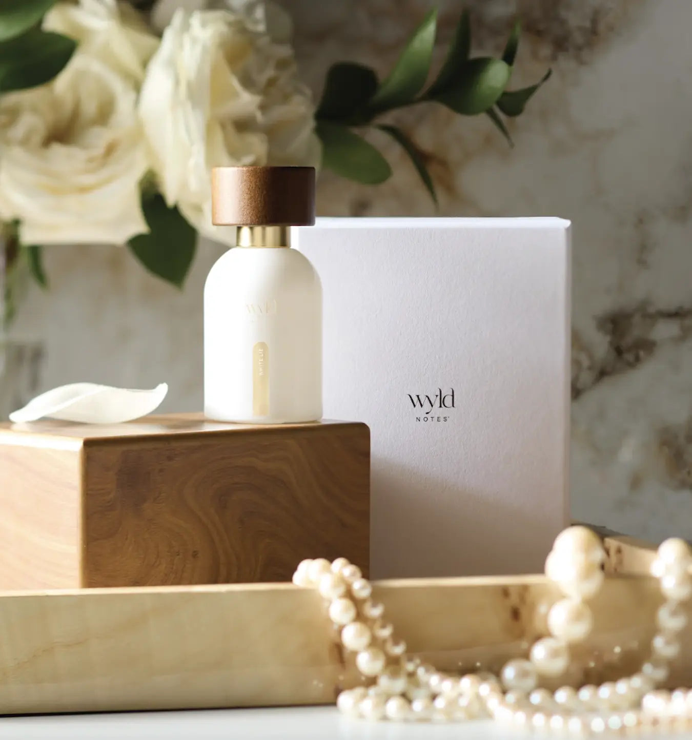 Wyld Notes White Lie clean fragrance met verpakking, parels en zachte quiet luxury uitstraling.