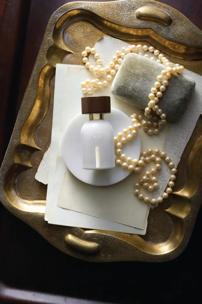 Wyld Notes White Lie parfum op een gouden tray met parels en zachte quiet luxury styling.